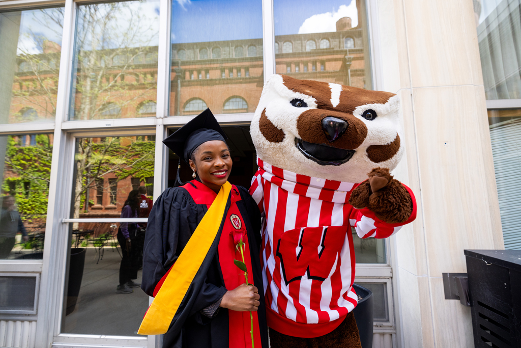 A graduate poses with Bucky Badger