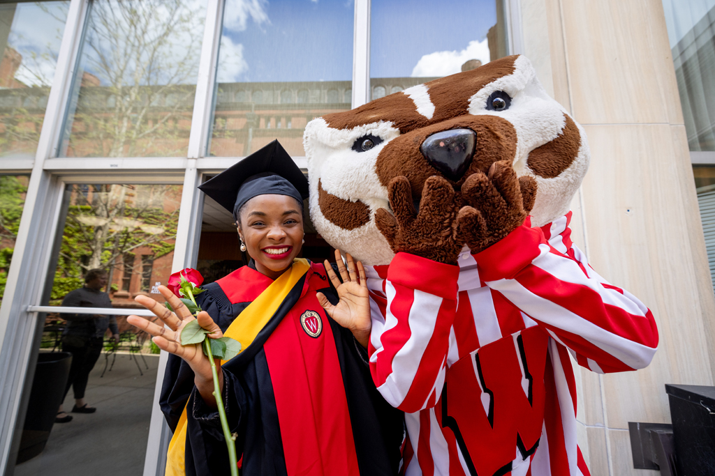 A graduate poses with Bucky Badger