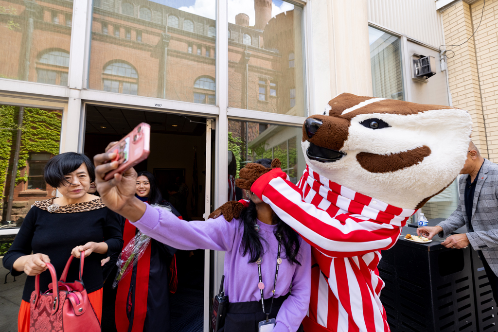 A graduate poses with Bucky Badger