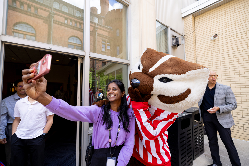 A graduate poses with Bucky Badger