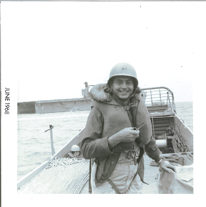 Robert Hammel on a boat wearing a military helmet.