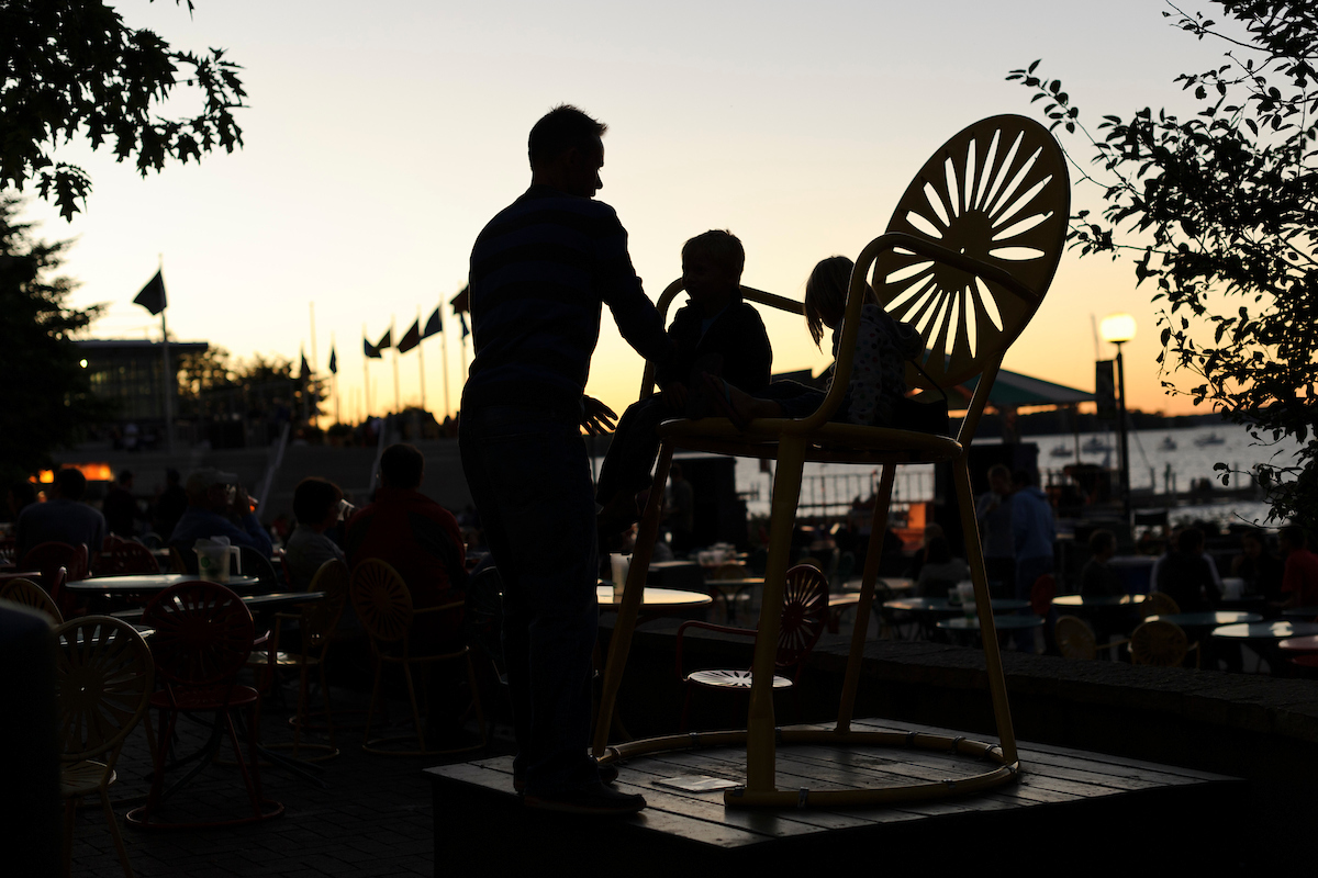 Silhouettes of father with two children on large terrace chair at Union Terrace