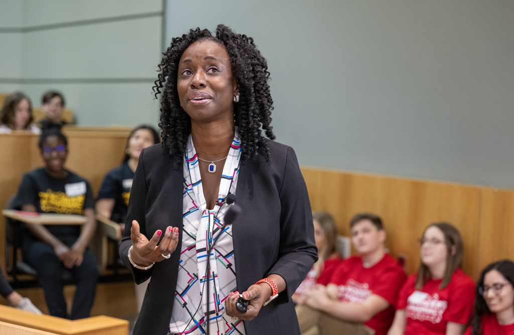 Olufunmilola Abraham speaks in front of a lecture hall filled with attendees.