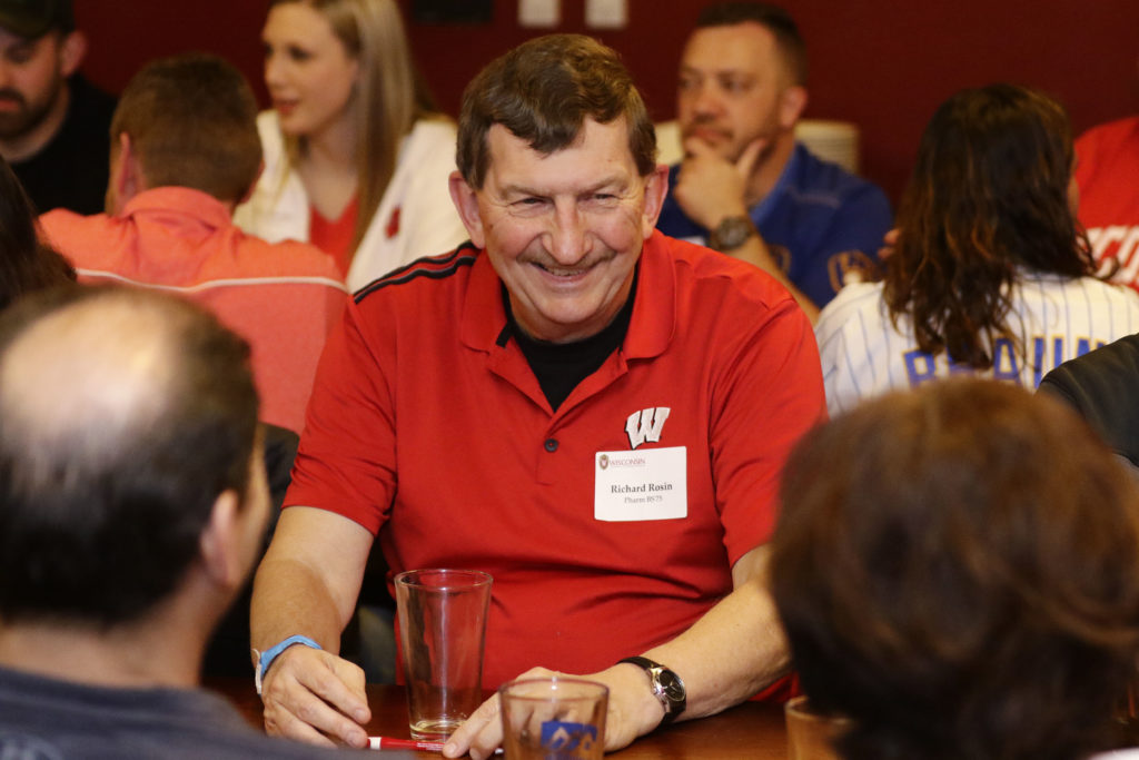 Alumni smiling together with drinks in front of them