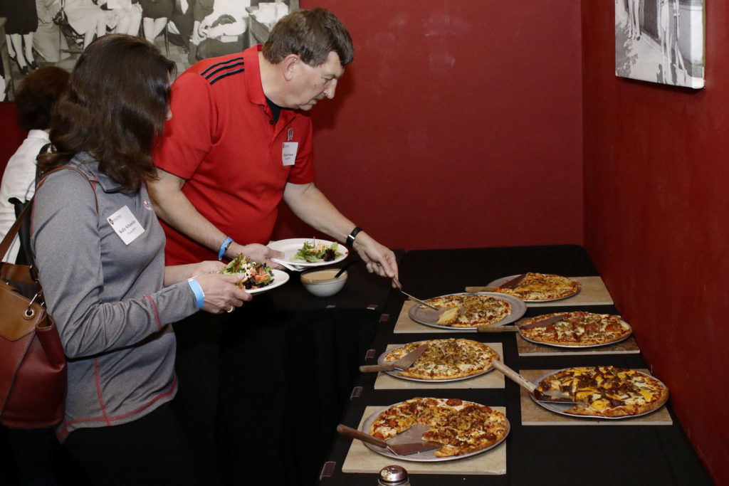 People taking pizza from table setup