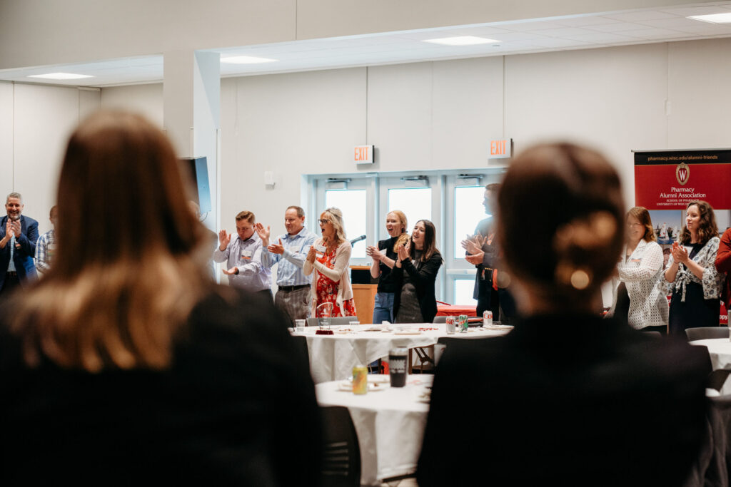 Alumni standing in a circle and applauding.