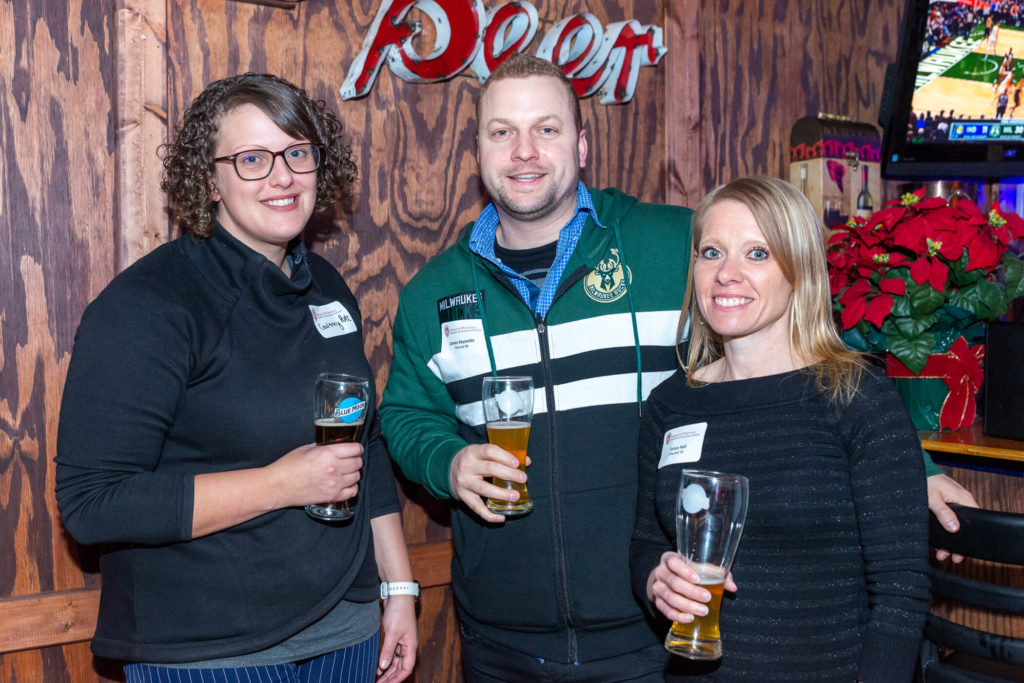 Courtney Putz, James Reynolds, and Tanya Hall all standing together with drinks in their hands