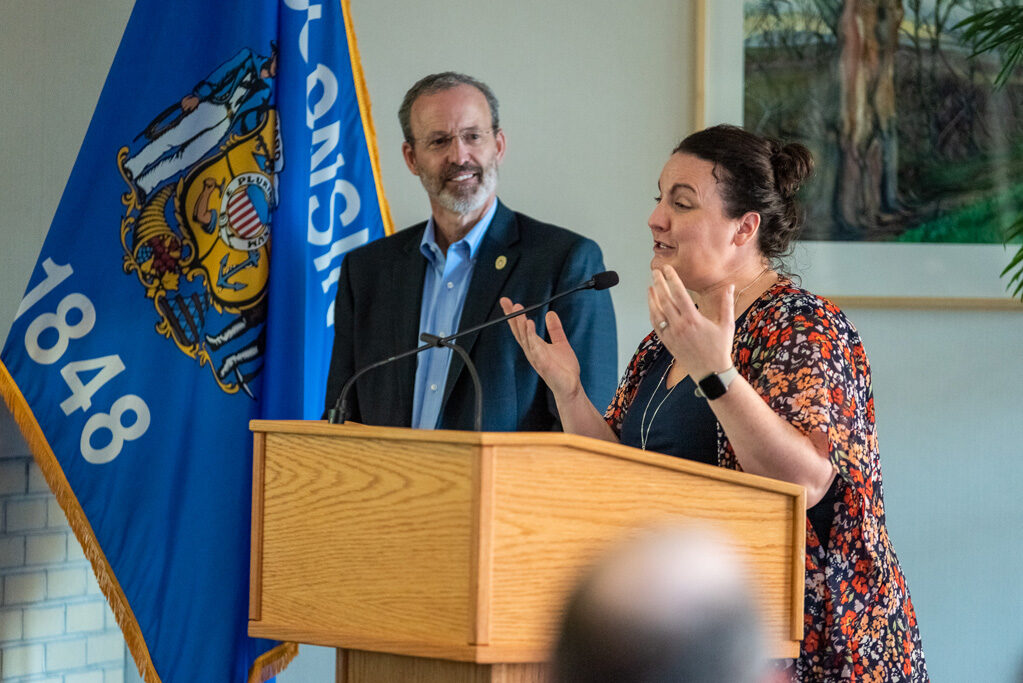 Faculty member speaking at podium gesturing their hands