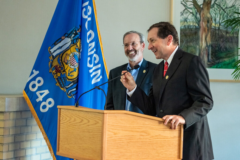 Dave Mott smiling with another faculty member at podium