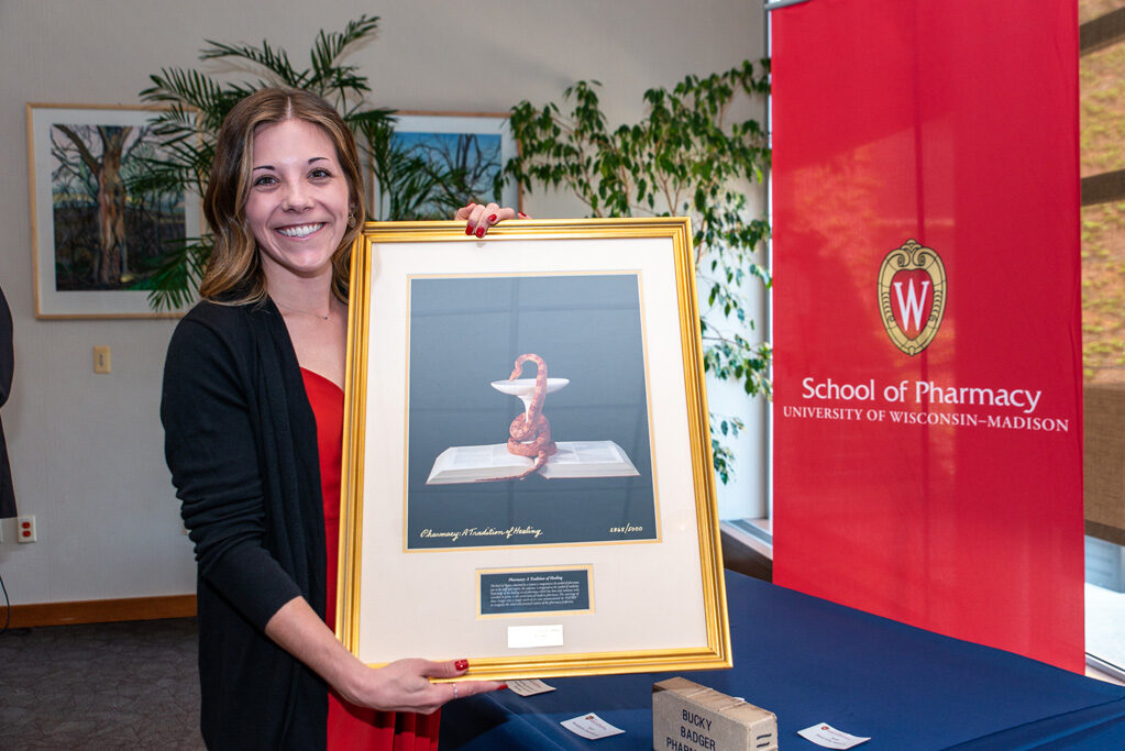 Graduate student holding up painting she received