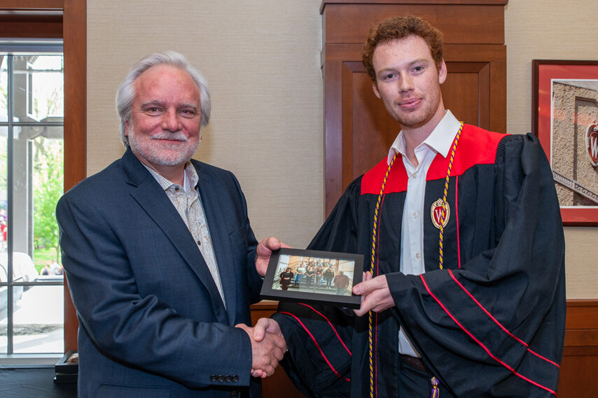 Graduate student holding a picture frame with prof. Jeffrey Johnson