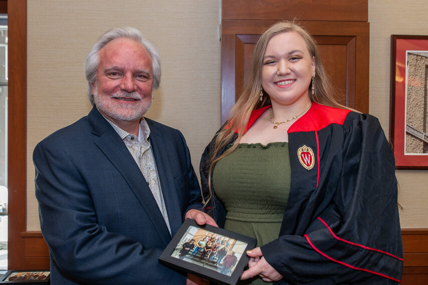 Graduate student holding a picture frame with prof. Jeffrey Johnson