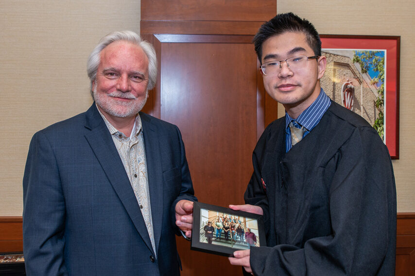 Graduate student holding a picture frame with prof. Jeffrey Johnson