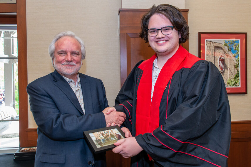 Graduate student holding a picture frame with prof. Jeffrey Johnson