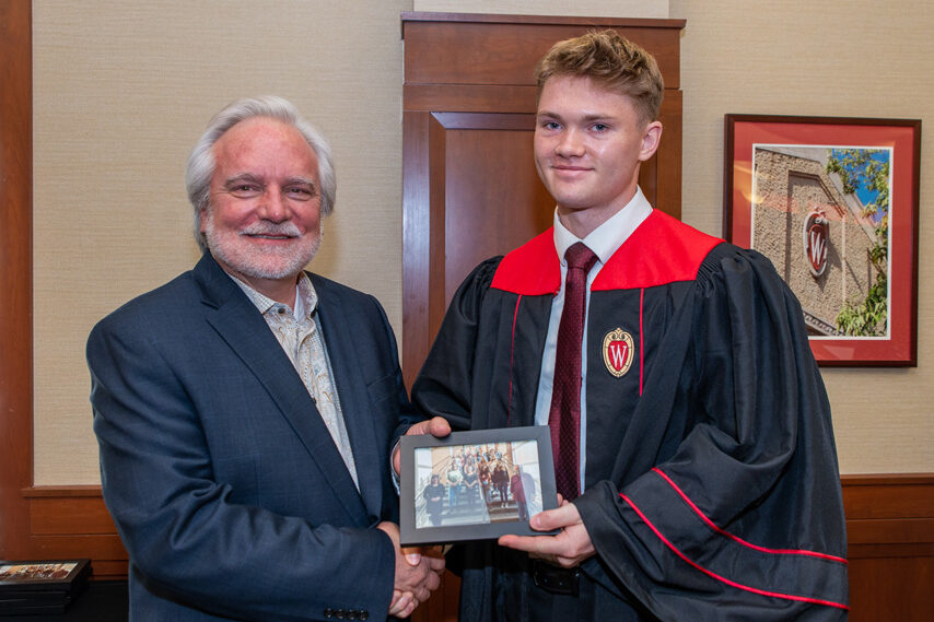 Graduate student holding a picture frame with prof. Jeffrey Johnson