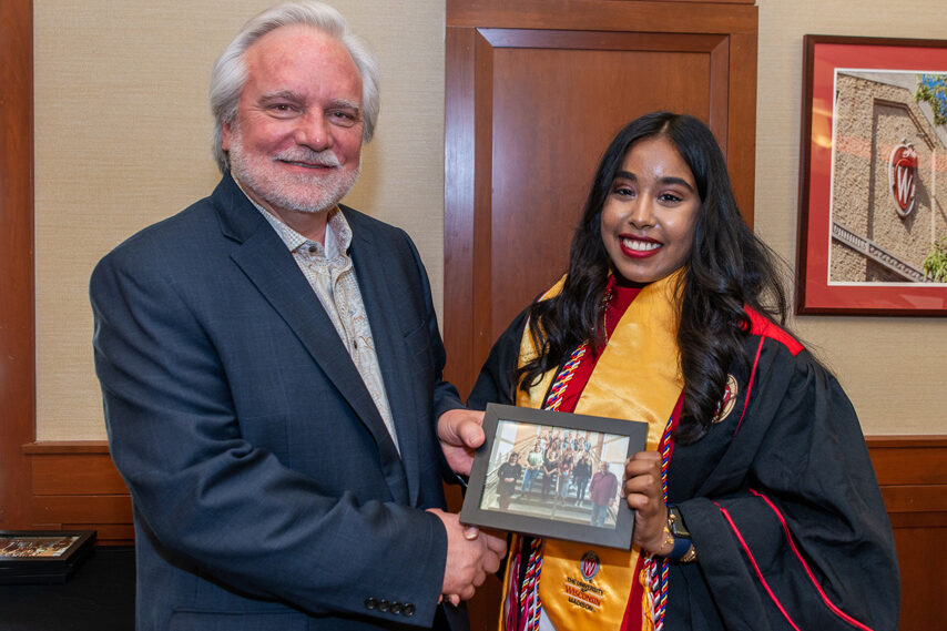 Graduate student holding a picture frame with prof. Jeffrey Johnson