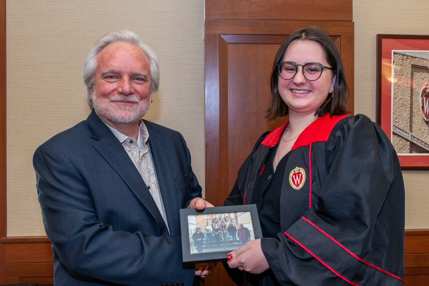 Graduate student holding a picture frame with prof. Jeffrey Johnson