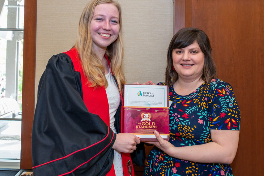 faculty member holding Merck Manual with graduate student