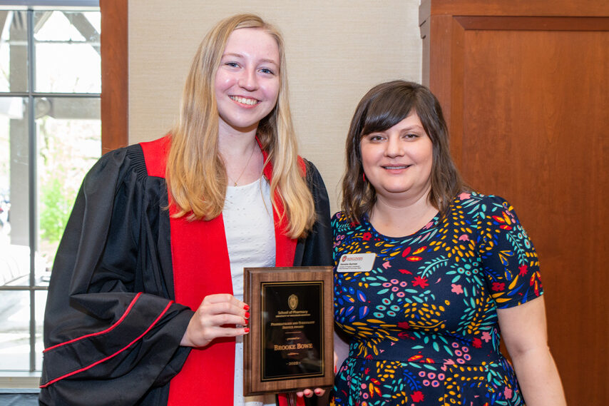 graduate student with faculty member holding an award