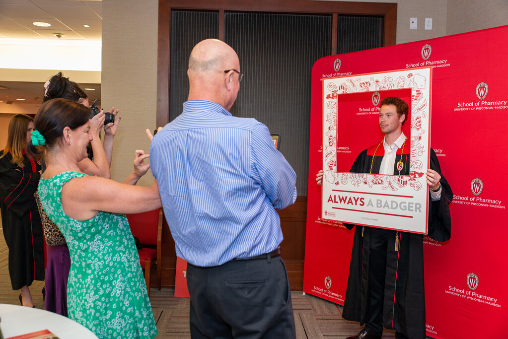 Graduated student using frame prop in front of red backdrop