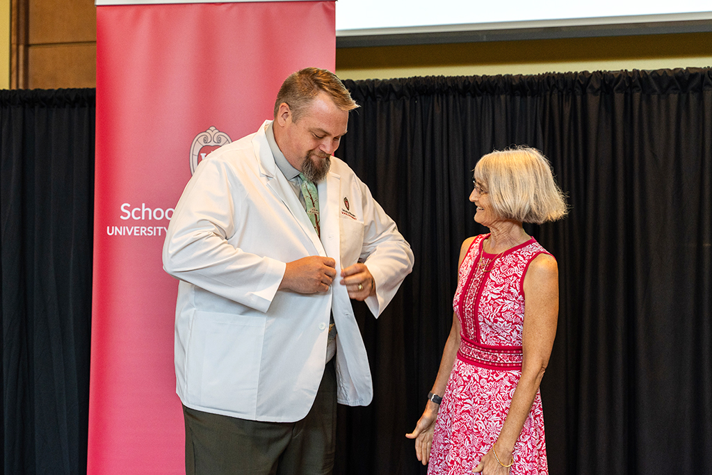 John Vetterli buttons his white coat next to Mara Kieser