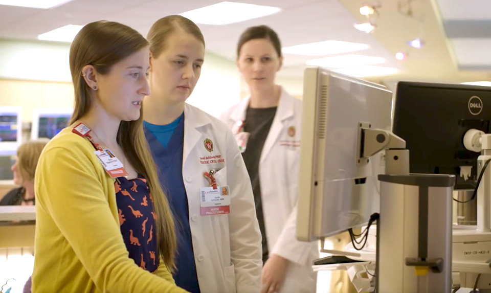 A pharmacist and nurse practitioner look at a patient's vitals and records in clinic