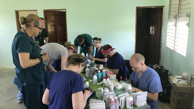 Alex Wontor with other students and pharmacists at table filled with supplies
