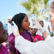 A volunteer helping children understand how to use an inhaler.