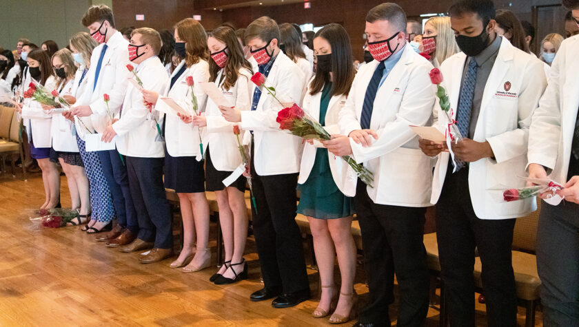 Pharm students holding roses and white coat ceremony pamphlets