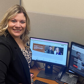 Kendra Isberner smiling at a desk with computers