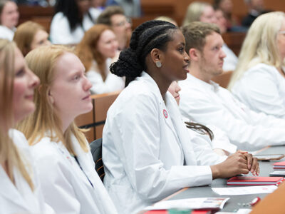 PharmD students in white coats sitting in a row