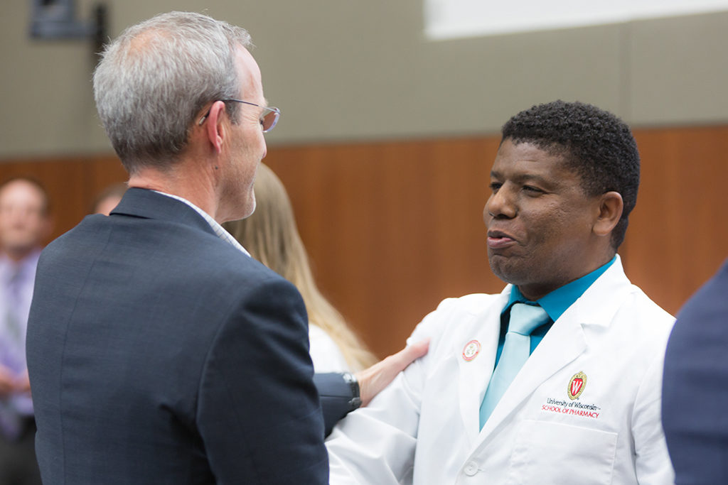 A student accepts pin from David Mott, professor of the School.