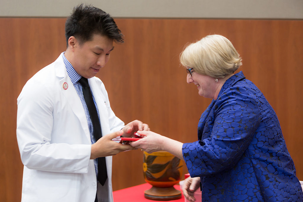 Associate Professor Karen Kopacek awards the pin to the students.