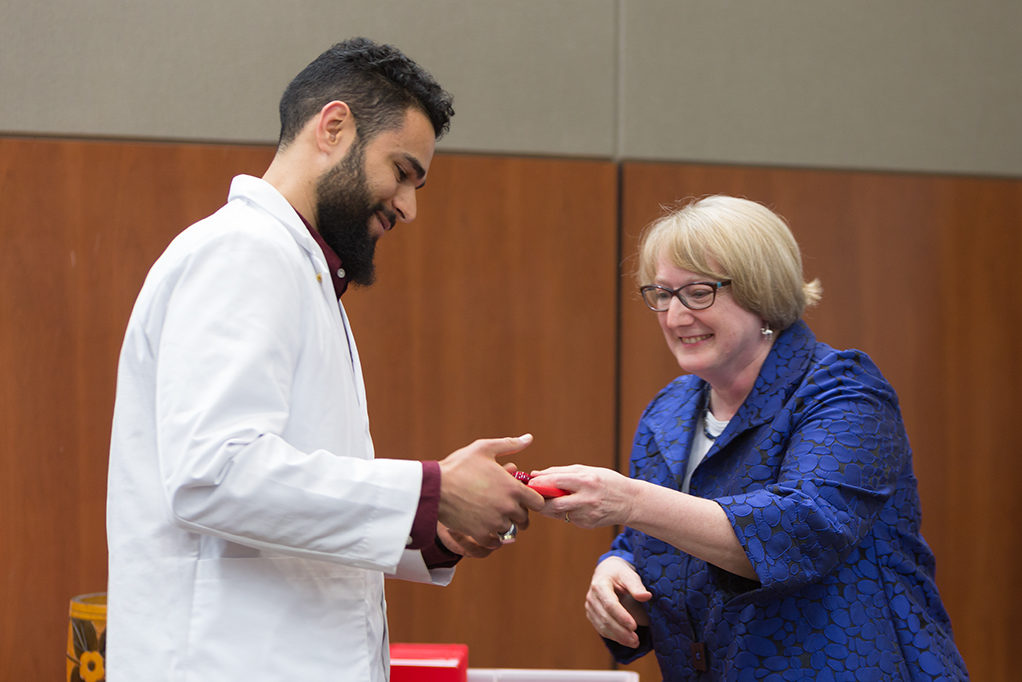 Associate Professor Karen Kopacek awards the pin to the students.