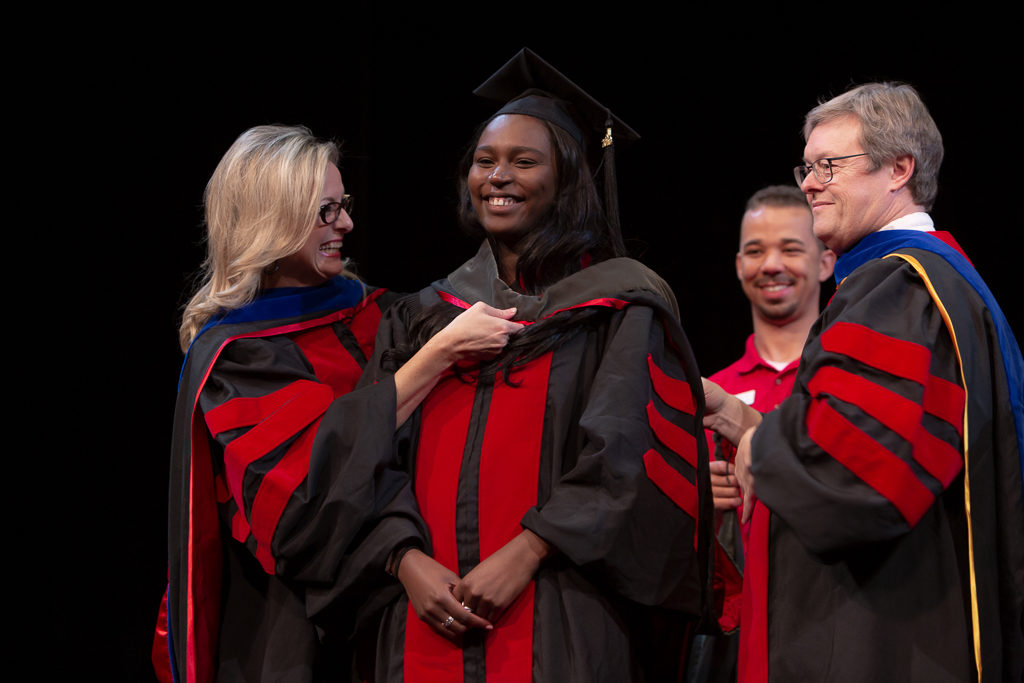 Students receive the hood for their graduation.