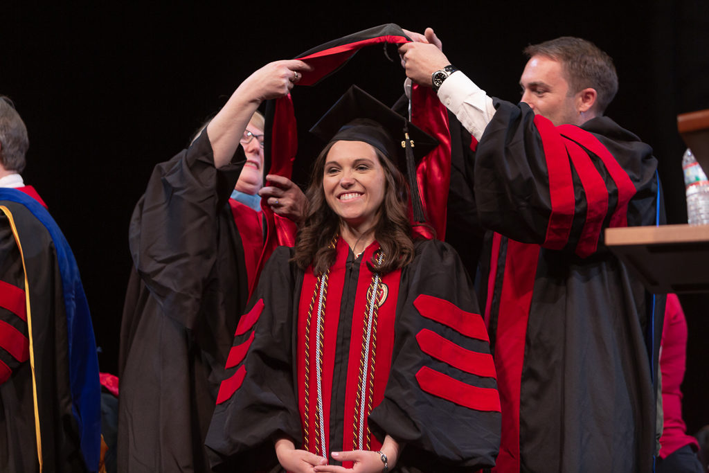 Students receive the hood for their graduation.