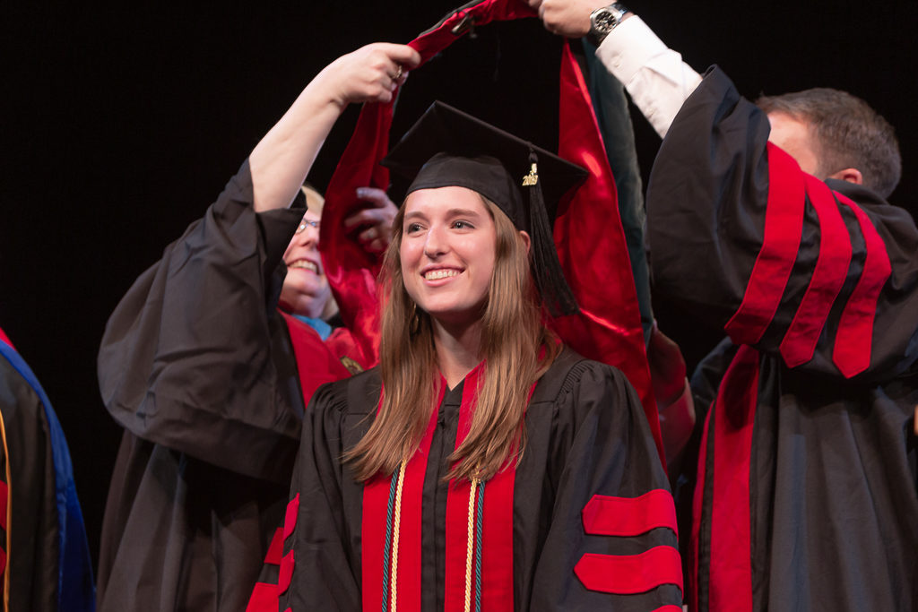 Students receive the hood for their graduation.