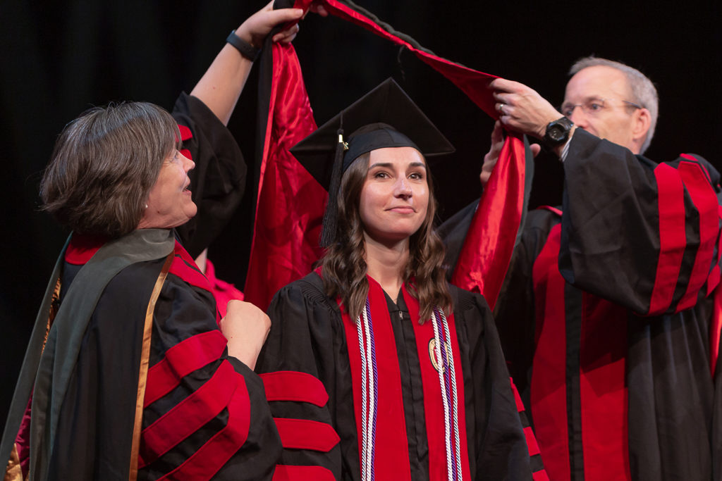 Students receive the hood for their graduation.