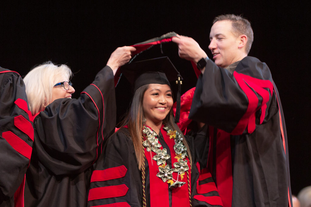 A student is awarded the hood from the school faculty.