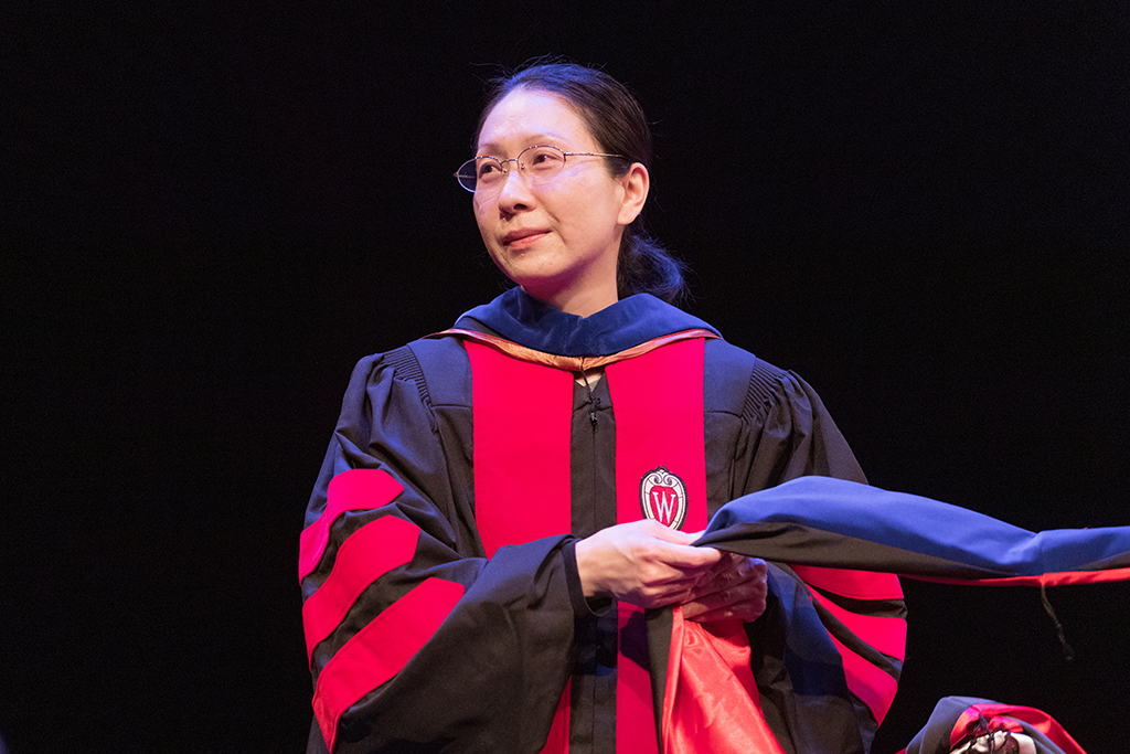 Faculty place a hood over a graduate's head.