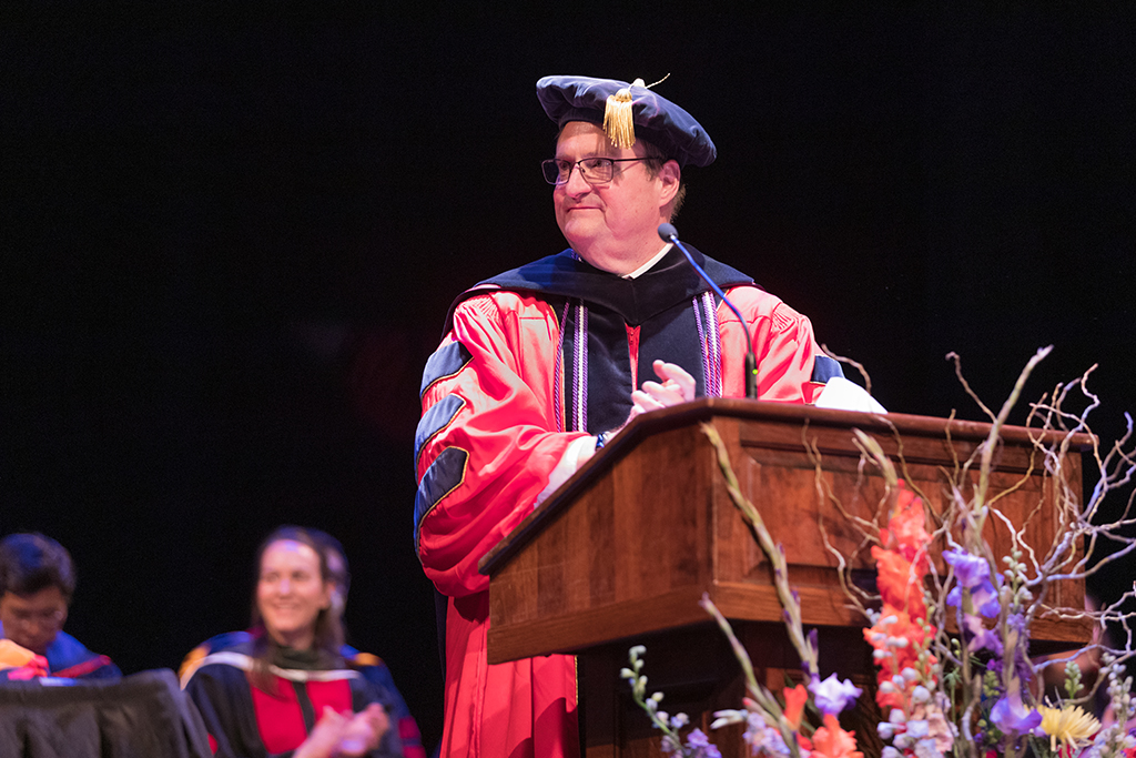 Dean Steve Swanson applauds at the podium.