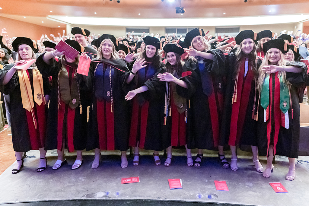 Inside, graduates are arm in arm at the end of the ceremony.