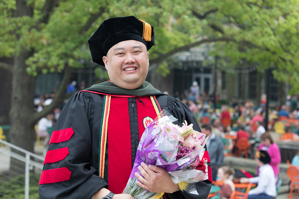 Graduate Mark Moua poses with a bouquet.