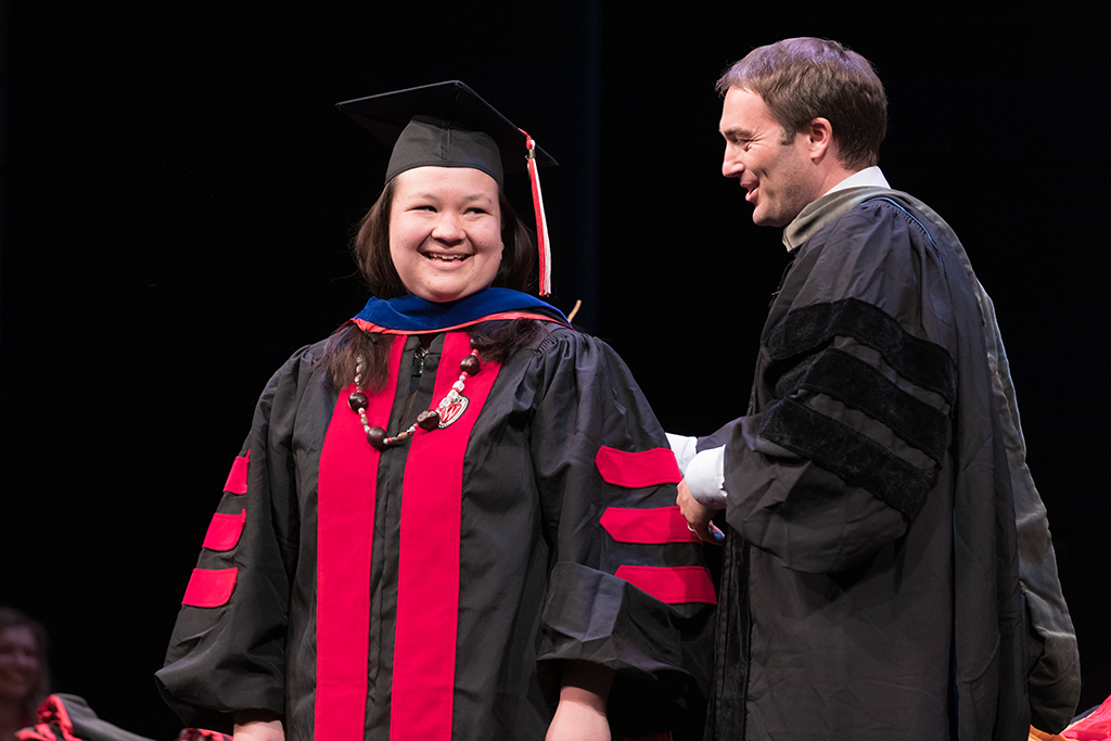 A professor at the School of Pharmacy bestowing a hood upon a graduate student at the Hooding Ceremony