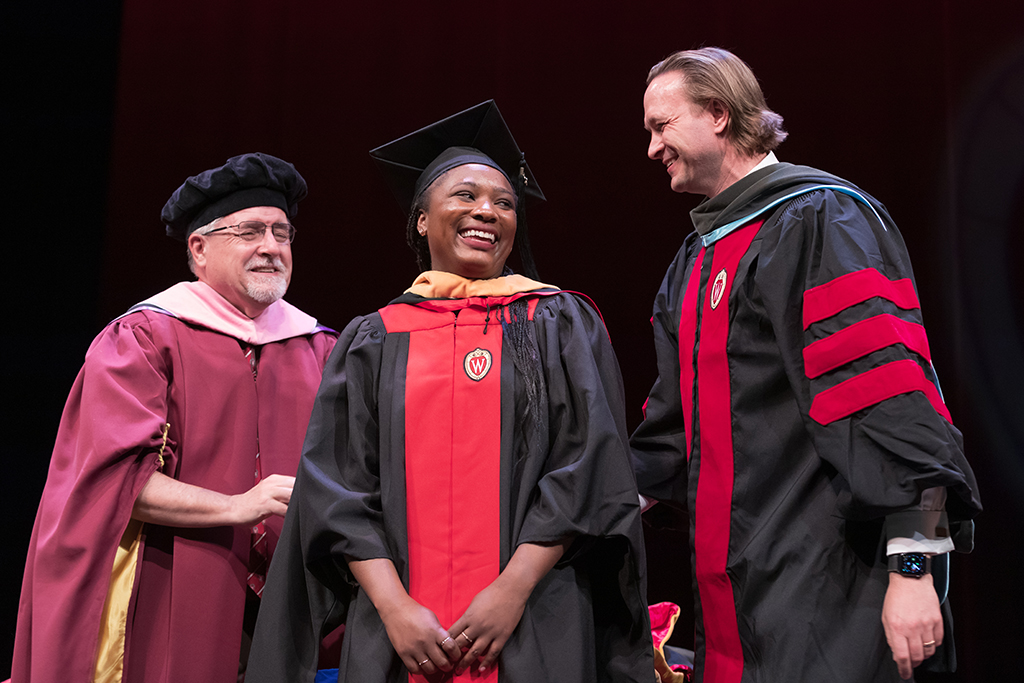 Assistant Dean Melgardt deVilliers and another professor putting the hood on a graduate student