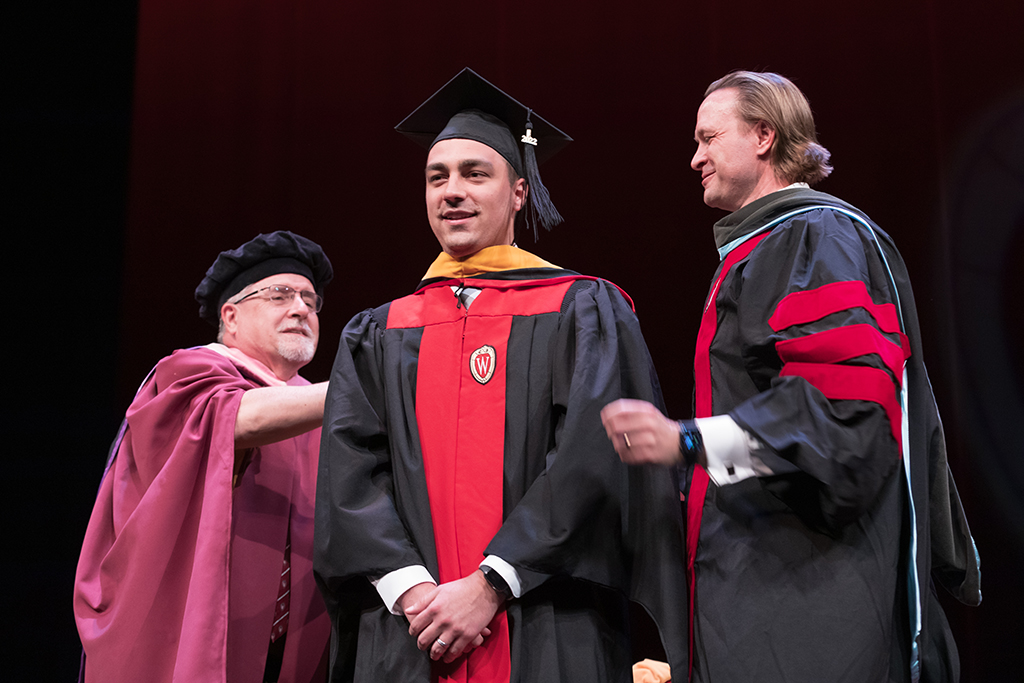 Assistant Dean Melgardt deVilliers and another professor putting the hood on a graduate student