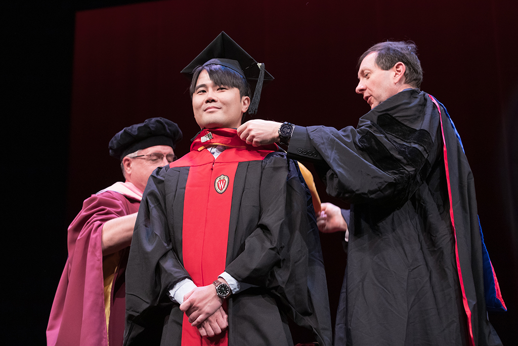 Assistant Dean Melgardt deVilliers and another professor putting the hood on a graduate student