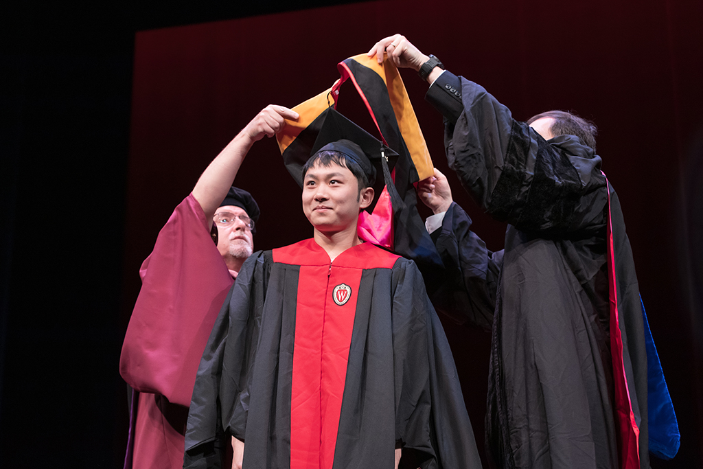 Assistant Dean Melgardt deVilliers and another professor putting the hood on a graduate student