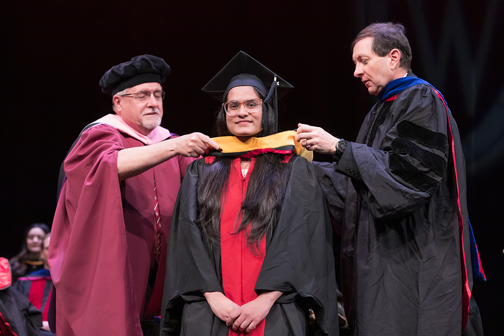 Assistant Dean Melgardt deVilliers and another professor putting the hood on a graduate student