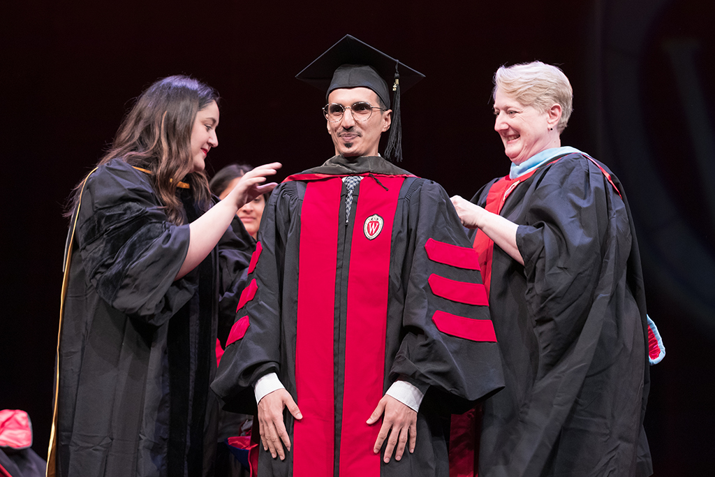 Class of 2022 PharmD graduate Bander Assiri receives his hood from Professors Marina Maes and Karen Kopacek